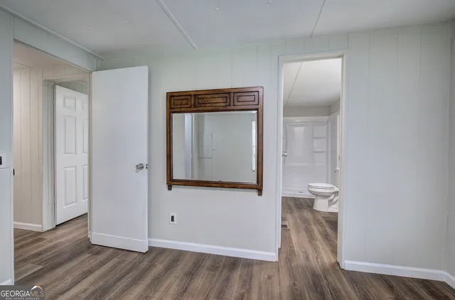 a view of a hallway with wooden floor and a bathroom