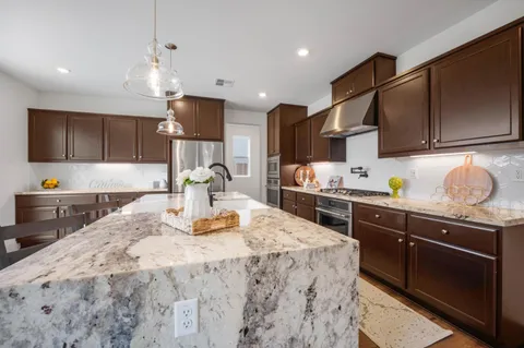 a kitchen with kitchen island granite countertop a sink cabinets and stainless steel appliances
