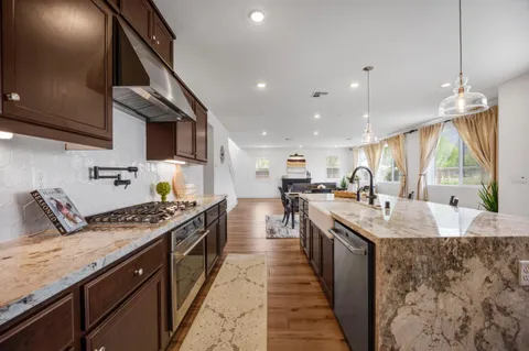 a kitchen with stainless steel appliances granite countertop a sink a stove and a wooden floors