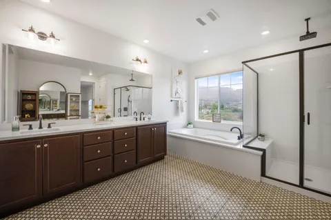 a bathroom with a tub a toilet a double vanity sink and mirror