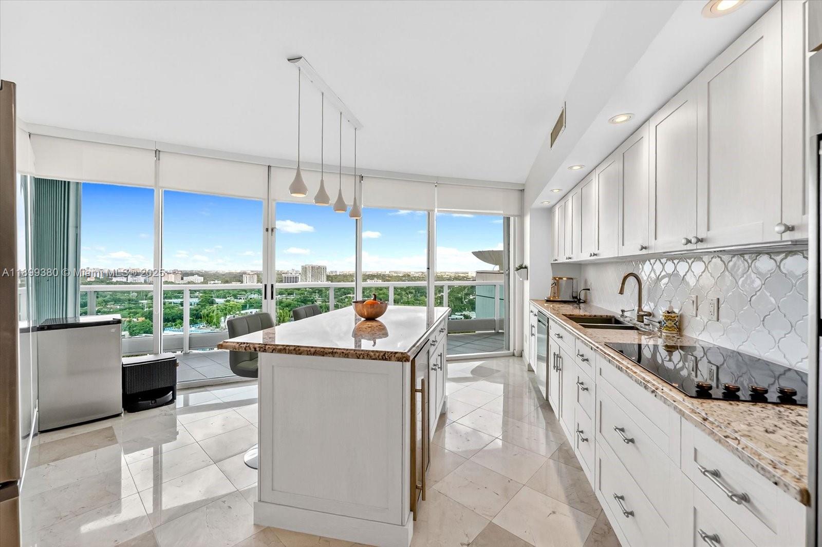 2127 Brickell Avenue, Unit 2005 Miami, FL 33129 - Photo 14 of 53 a kitchen with stainless steel appliances kitchen island a large window a sink and cabinets