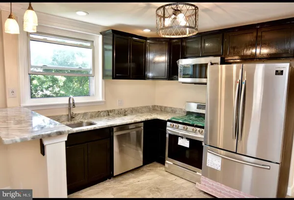 a kitchen with stainless steel appliances granite countertop a refrigerator a sink dishwasher a stove and white cabinets with wooden floor