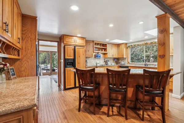a dining room with stainless steel appliances granite countertop wooden floor a large window and kitchen view