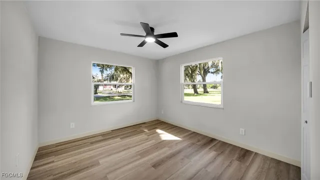 a view of empty room with wooden floor and fan