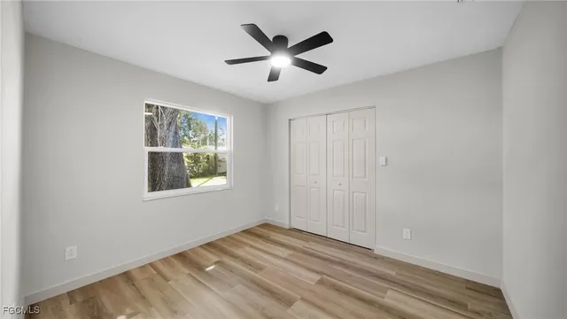 a view of an empty room with wooden floor and a ceiling fan