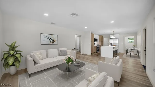 a living room with furniture potted plant and kitchen view