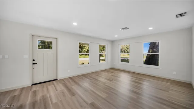 an empty room with wooden floor and windows