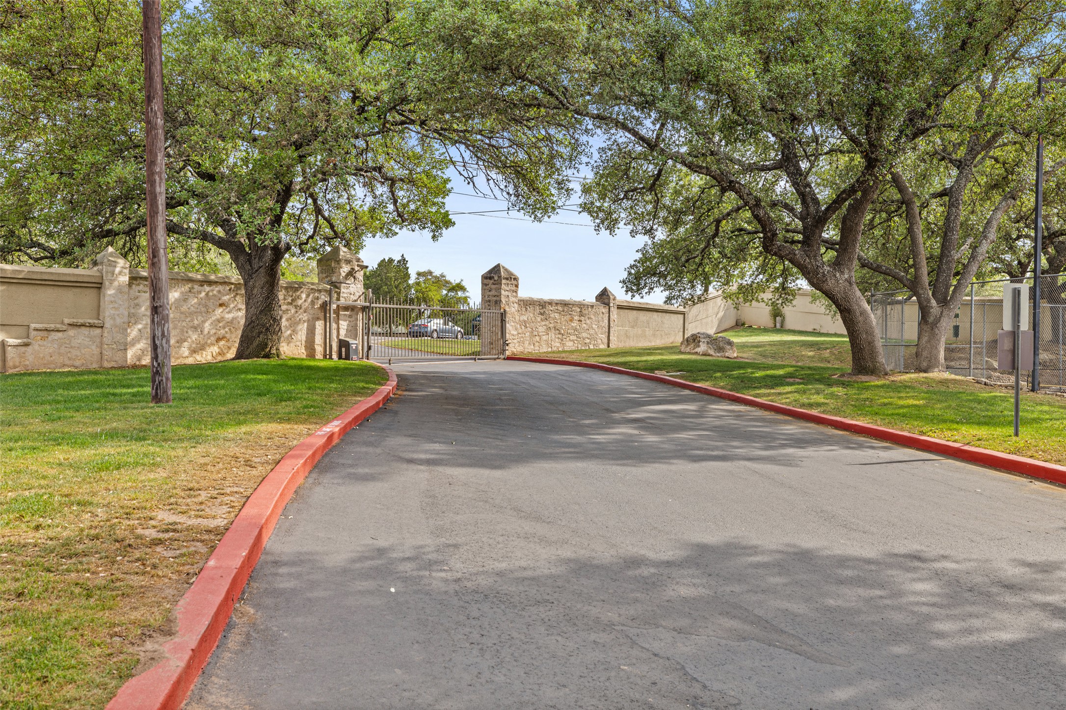 2918 Ranch To Market Road 620, Unit O282 Austin, TX 78734 - Photo 34 of 40 View of road featuring a gated entry, curbs, and a gate