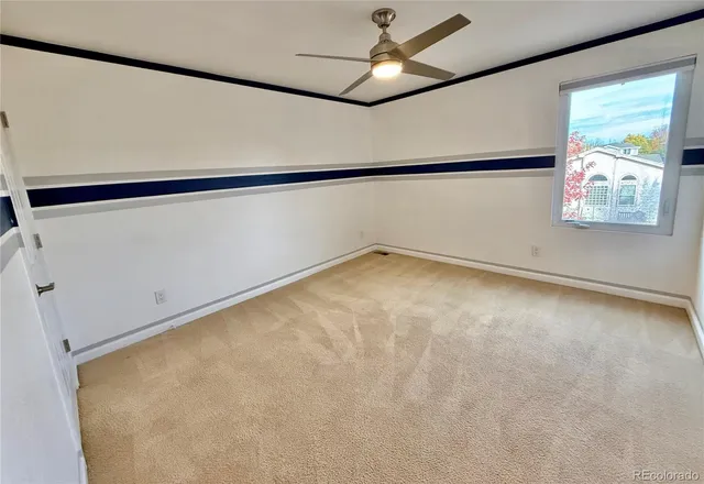 a view of an empty room with a window and a ceiling fan