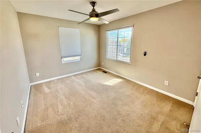 an empty room with windows and ceiling fan