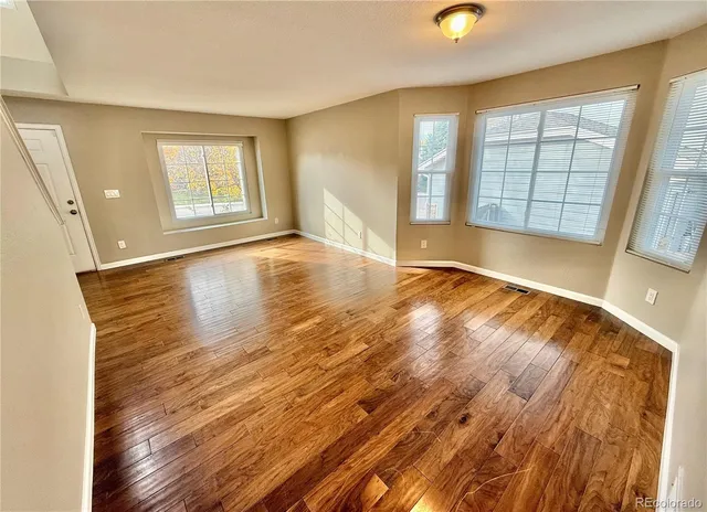 an empty room with wooden floor and windows