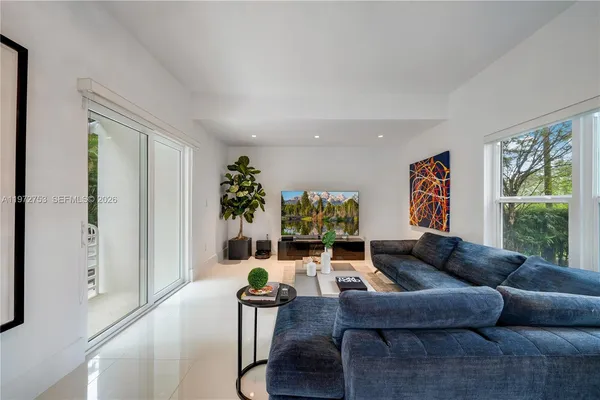a living room with furniture potted plant and a large window