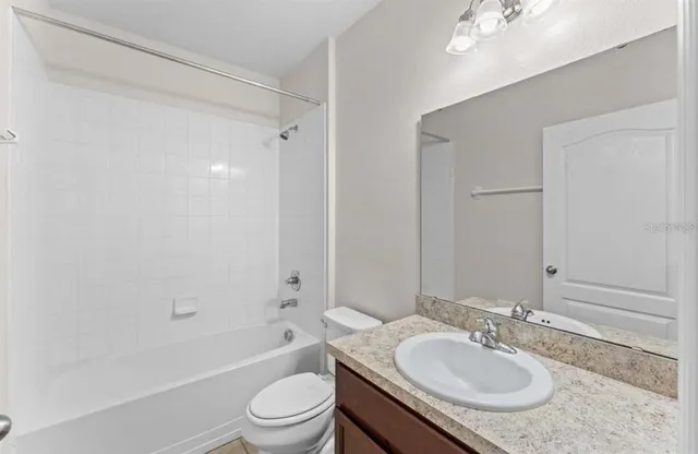 a bathroom with a granite countertop sink toilet mirror and shower