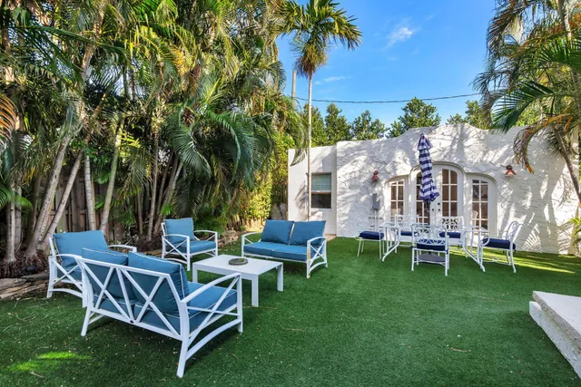 a view of a patio with table and chairs potted plants and a large tree