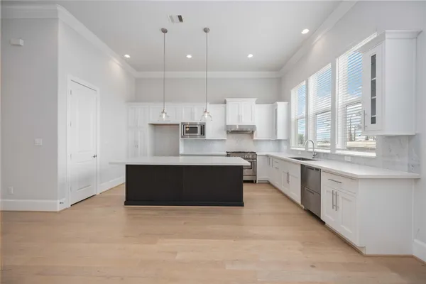a large kitchen with stainless steel appliances kitchen island granite countertop a large counter top a sink a stove a refrigerator and cabinets