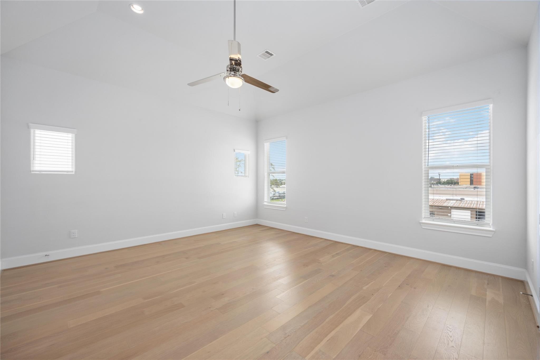 10919 Grove Tree Lane Houston, TX 77043 - Photo 25 of 43 an empty room with wooden floor chandelier fan and windows