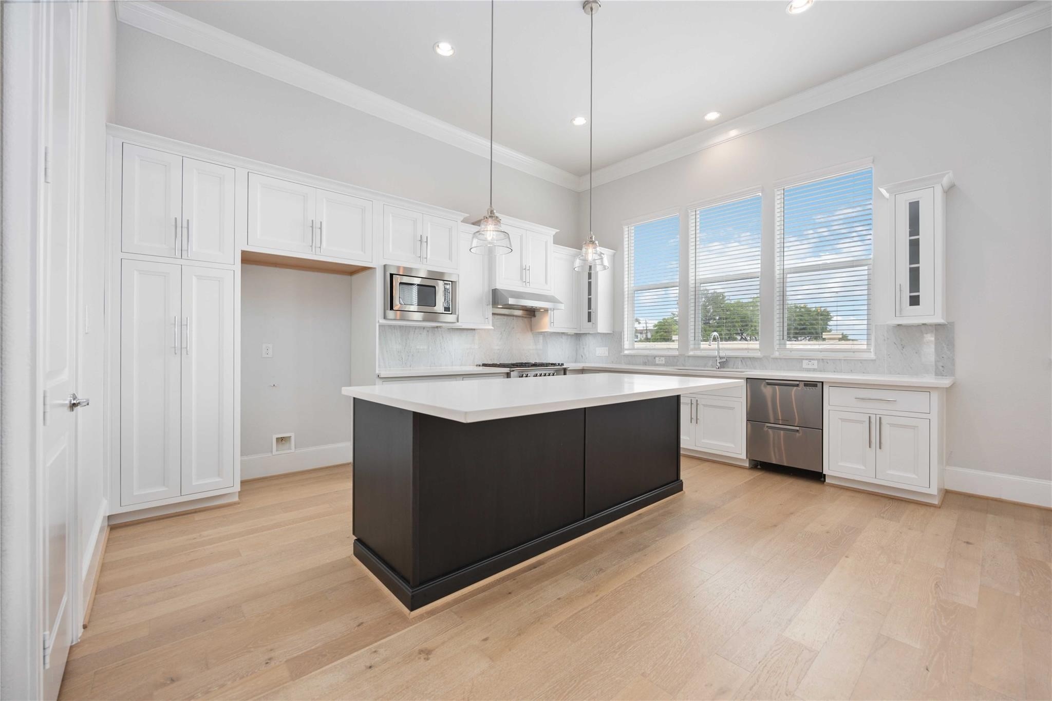 10919 Grove Tree Lane Houston, TX 77043 - Photo 3 of 43 a kitchen with a white cabinets counter space a sink and a window