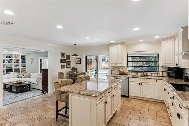 a kitchen with stainless steel appliances granite countertop a stove top oven a sink a refrigerator and white cabinets with wooden floor