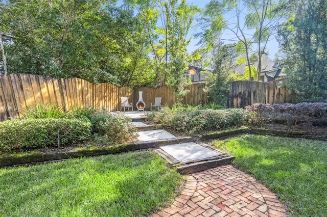 a view of a backyard with potted plants and large trees