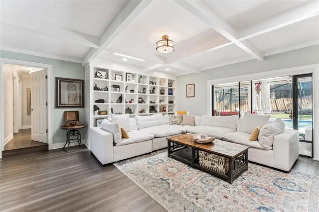 a living room with furniture a chandelier and wooden floor