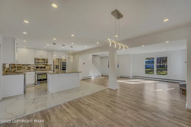 a large kitchen with white cabinets sink and stainless steel appliances