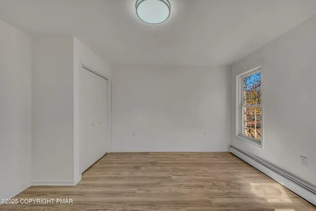 a view of empty room with window and wooden floor