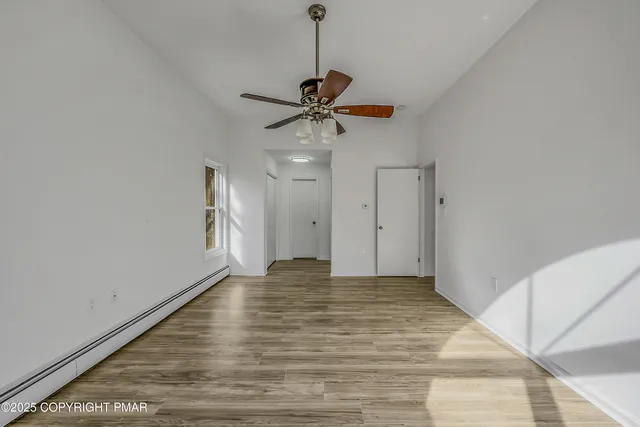 a view of an empty room with a ceiling fan and window