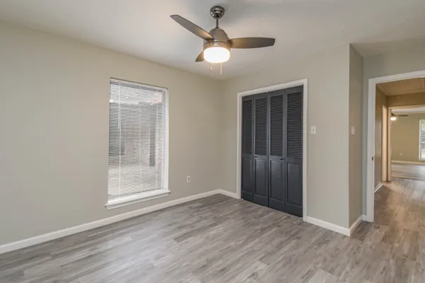 an empty room with wooden floor and windows