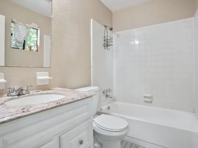 a bathroom with a granite countertop sink a toilet and bathtub