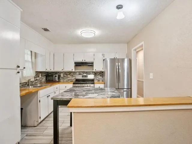 a kitchen with stainless steel appliances granite countertop a sink a stove a refrigerator a center island and cabinets
