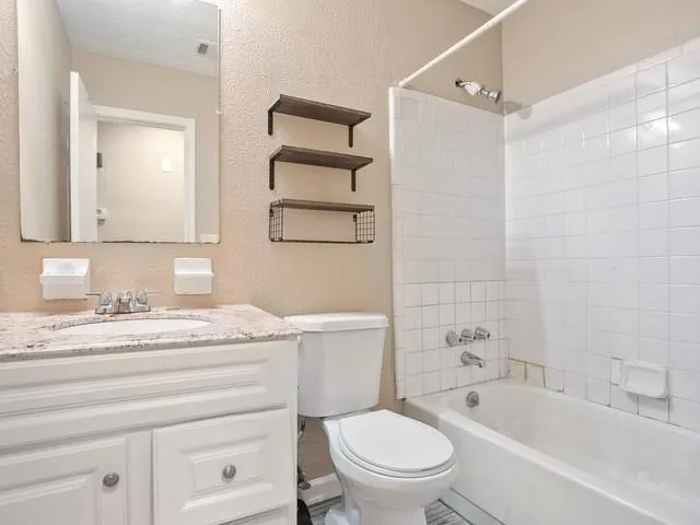 a bathroom with a granite countertop toilet sink and mirror