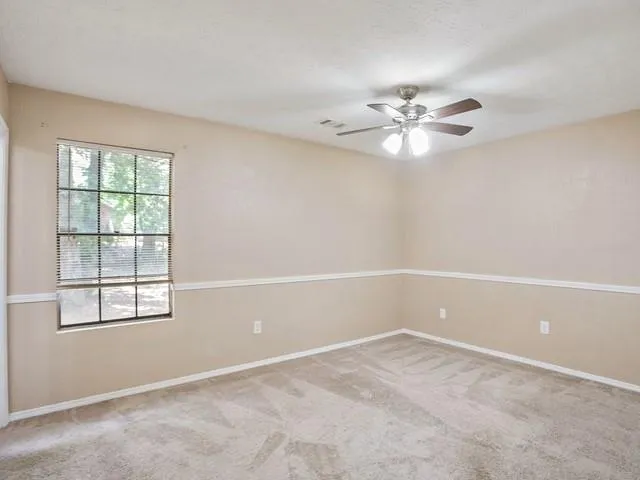 an empty room with a window and a fan