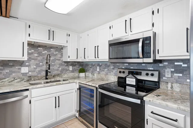 a kitchen with stainless steel appliances granite countertop white cabinets a stove a sink and dishwasher