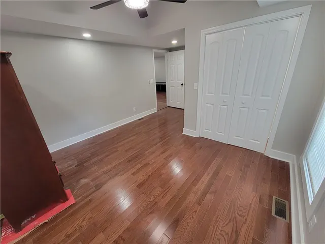 an empty room with wooden floor and chandelier fan