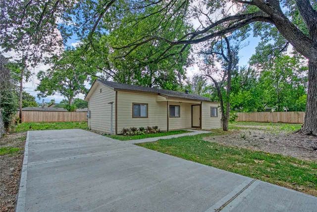 a view of a house with a yard and large trees