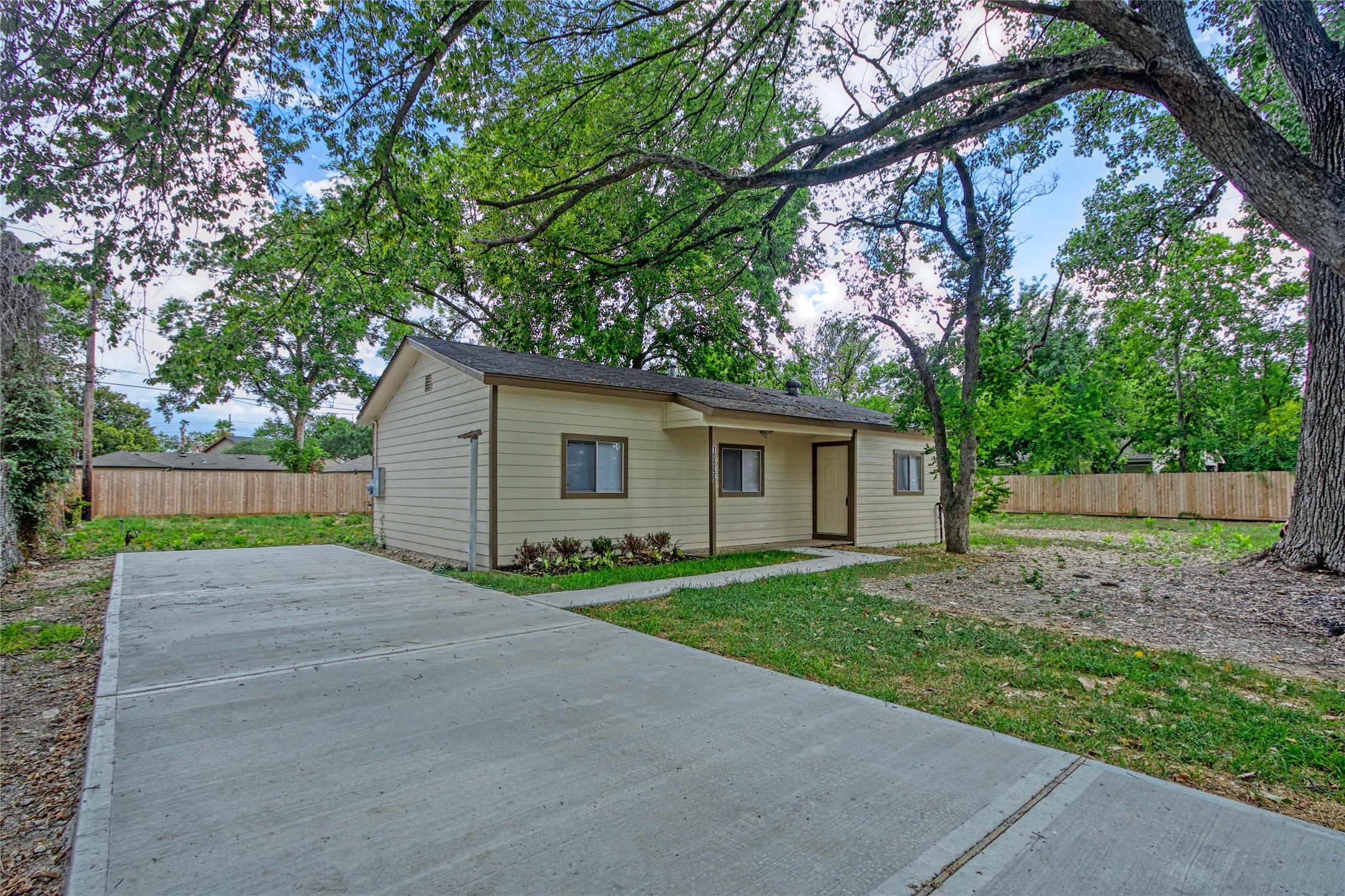 a view of a house with a yard and large trees