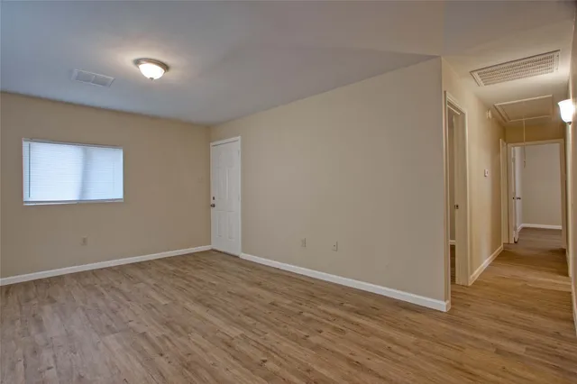 a view of an empty room with wooden floor and closet