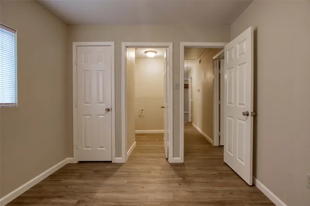 a view of an empty room with wooden floor and a bathroom