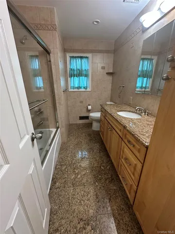 a bathroom with a granite countertop sink a mirror and a toilet