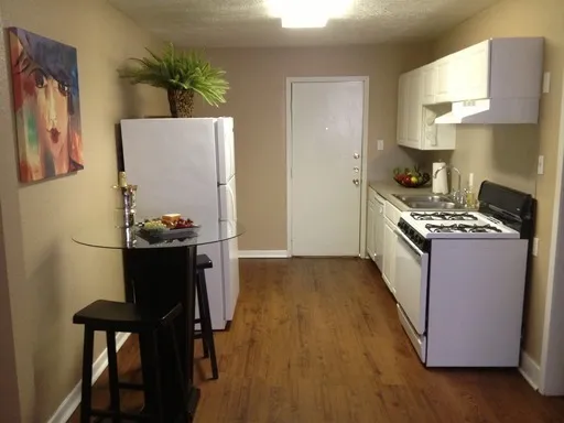 a kitchen with stainless steel appliances granite countertop a stove a refrigerator a sink a dining table and chairs with wooden floor