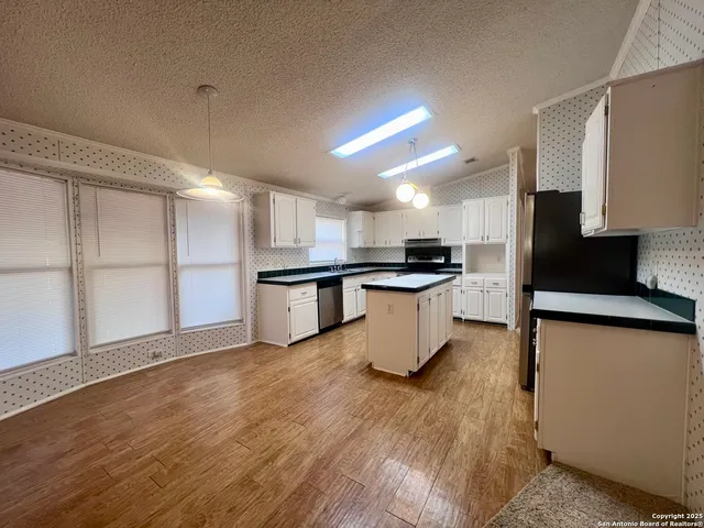 a kitchen with stainless steel appliances wooden floor and a refrigerator
