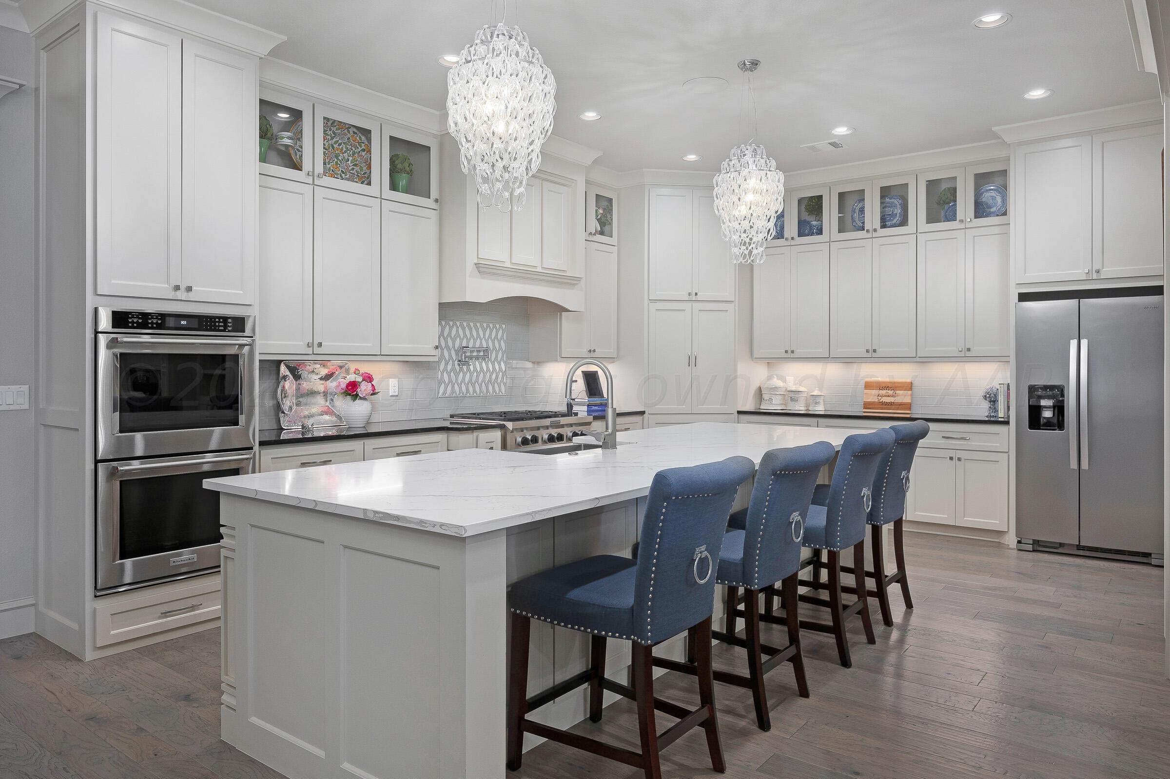 8307 Georgetown Drive Amarillo, TX 79119 - Photo 3 of 46 a kitchen with stainless steel appliances granite countertop a stove top oven a refrigerator a sink and a dining table with wooden floor