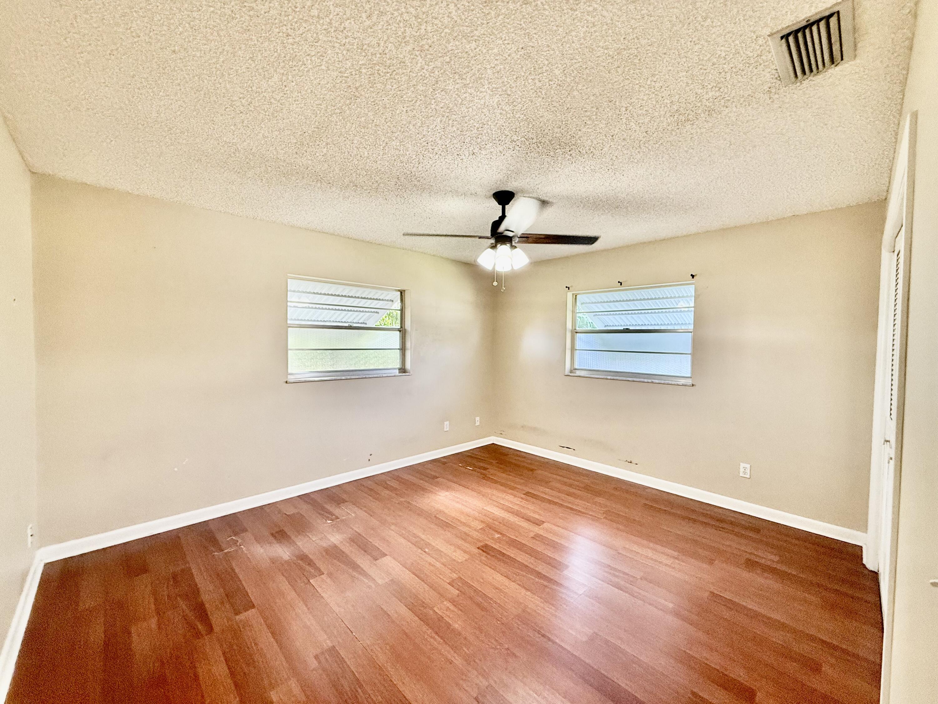 612 Coconut Avenue North Port St. Lucie, FL 34952 - Photo 16 of 32 an empty room with wooden floor chandelier fan and windows