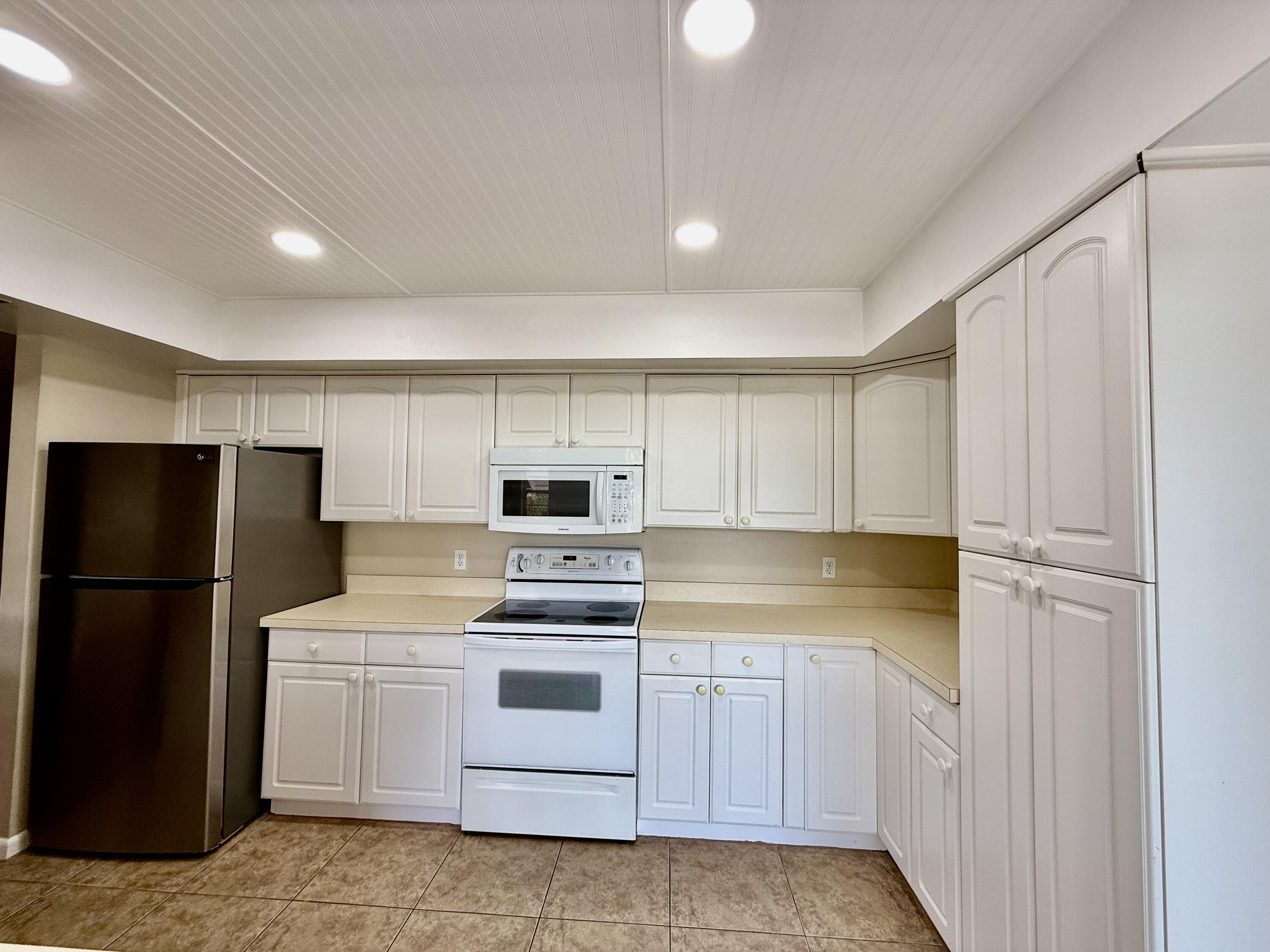 612 Coconut Avenue North Port St. Lucie, FL 34952 - Photo 6 of 32 a kitchen with a refrigerator a stove and white cabinets