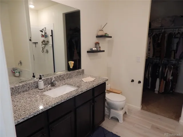 a bathroom with a granite countertop sink a toilet and a shower