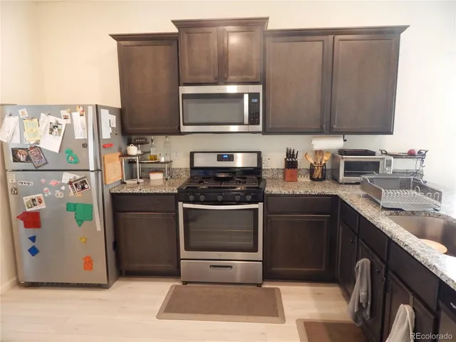 a kitchen with stainless steel appliances granite countertop a stove a sink and a microwave