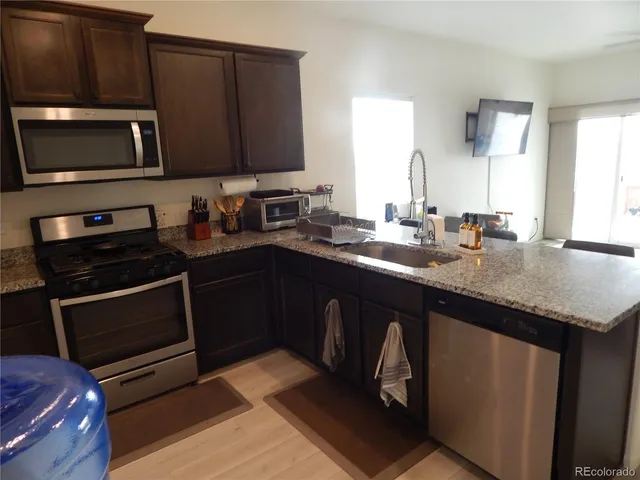 a kitchen with granite countertop stainless steel appliances a stove a sink a microwave and wooden cabinets