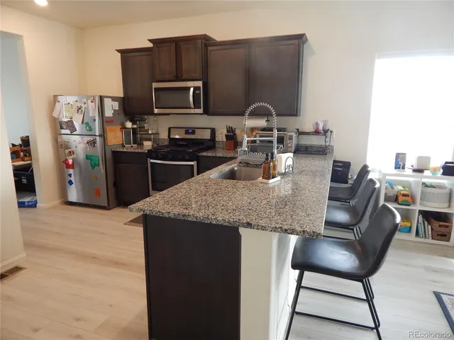 a kitchen with granite countertop kitchen island stainless steel appliances a refrigerator a stove a sink a dining table and chairs