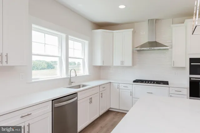 a kitchen with kitchen island a counter top space wooden floor and stainless steel appliances