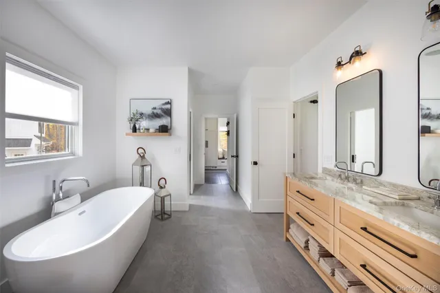 a bathroom with a granite countertop tub double vanity sink and a window